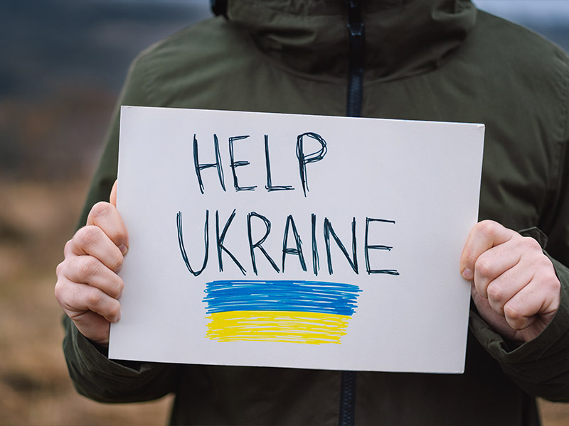 a child holding a hand written with the text HELP UKRAINE